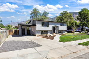 Split foyer home with concrete driveway, a mountain view, brick siding, and an attached carport