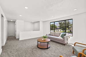 Carpeted living room with recessed lighting and a textured ceiling