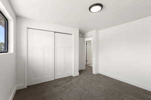 Unfurnished bedroom with dark colored carpet and a closet