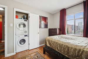 Bedroom featuring a textured ceiling, hardwood / wood-style floors, and stacked washing machine and dryer