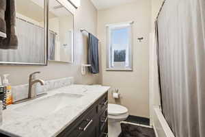 Full bathroom featuring shower / tub combo with curtain, vanity, and dark tile patterned flooring