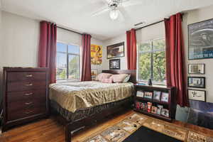 Bedroom featuring dark wood-style flooring, a textured ceiling, multiple windows, and ceiling fan