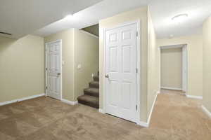 Finished below grade area with light carpet, stairs, and a textured ceiling