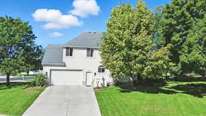 View of front of property featuring a shingled roof, a garage, a front yard, driveway, and stucco siding