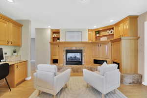 Living area featuring built in desk, built in shelves, light wood finished floors, a tile fireplace, and recessed lighting
