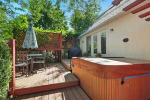 Wooden deck with a hot tub, a grill, and outdoor dining space