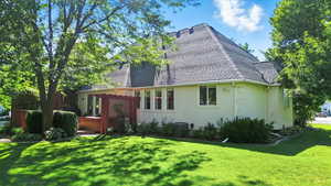 Rear view of property featuring a hot tub, a yard, and stucco siding