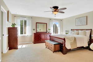 Bedroom with multiple windows, light carpet, and ceiling fan