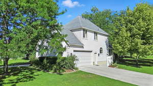 View of home's exterior featuring a shingled roof, a yard, stucco siding, and concrete driveway