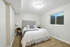 Carpeted bedroom featuring baseboards and a textured ceiling