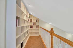 Hallway with light carpet, lofted ceiling, recessed lighting, and an upstairs landing