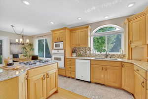 Kitchen with light brown cabinets, a chandelier, light wood-style flooring, plenty of natural light, and recessed lighting