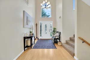 Foyer entrance featuring light wood finished floors, a high ceiling, a chandelier, and stairs