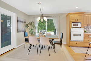 Dining room with light wood-style floors, a chandelier, and recessed lighting