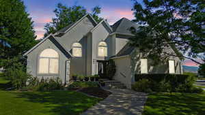 View of front facade featuring a yard, stucco siding, and roof with shingles