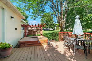 Wooden terrace featuring a covered hot tub and outdoor dining area