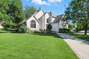 View of front of home with stucco siding, a front yard, and a shingled roof