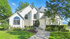 View of front of house with a front lawn, a shingled roof, and stucco siding