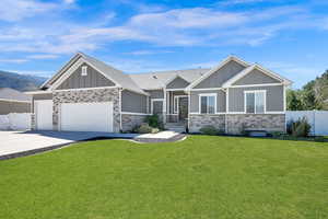 Craftsman-style home featuring board and batten siding, stone siding, a garage, and concrete driveway