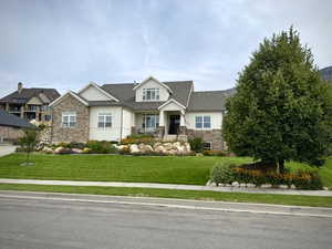 Craftsman-style home featuring stone siding, a front yard, and board and batten siding