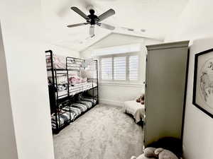 Bedroom with light colored carpet, lofted ceiling, and a ceiling fan