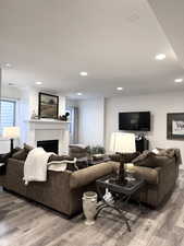 Living area with a fireplace, light wood-type flooring, and recessed lighting