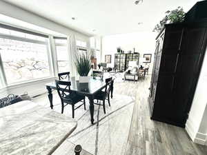 Dining room with light wood-style flooring, a textured ceiling, and recessed lighting