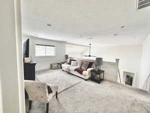 Living area with carpet, ceiling fan, and a textured ceiling
