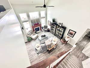 Living area with a glass covered fireplace, high vaulted ceiling, wood finished floors, and ceiling fan