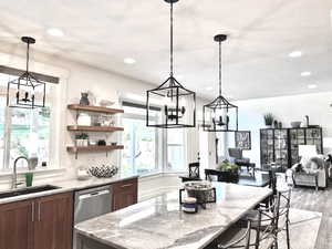 Kitchen with a chandelier, light stone countertops, pendant lighting, a kitchen bar, and recessed lighting