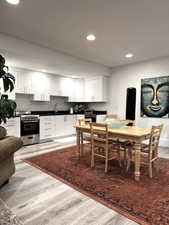 Kitchen with white cabinets, stainless steel range with gas cooktop, recessed lighting, light wood-style floors, and dark countertops