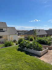 View of green lawn featuring a vegetable garden and a residential view
