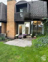 Rear view of house with a balcony, a lawn, and a chimney