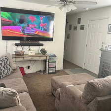 Living area featuring a ceiling fan and carpet