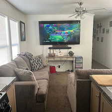 Living room with carpet, ceiling fan, and a decorative wall
