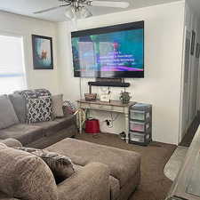 Living area featuring carpet and a ceiling fan