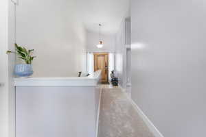 Hallway with high vaulted ceiling and light carpet