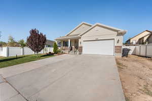 View of front facade with a porch, a garage, brick siding, and driveway
