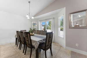 Dining room featuring vaulted ceiling, light tile patterned flooring, and a chandelier