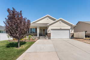 Craftsman-style home featuring covered porch, brick siding, an attached garage, driveway, and board and batten siding