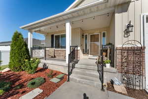 View of exterior entry with board and batten siding and a porch