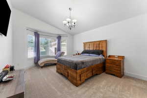 Bedroom with vaulted ceiling, light carpet, and a chandelier