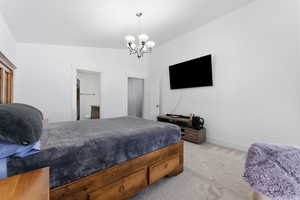 Bedroom featuring light carpet, vaulted ceiling, connected bathroom, and a chandelier