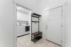 Laundry area featuring light tile patterned floors, independent washer and dryer, and cabinet space