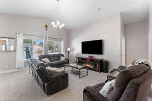 Carpeted living area with lofted ceiling and a chandelier