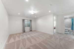Empty room with light colored carpet and recessed lighting