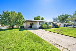 Ranch-style home featuring a front yard, concrete driveway, and a carport