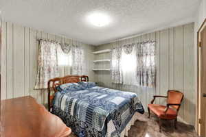 Bedroom with wood walls and a textured ceiling