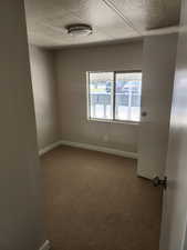 Carpeted empty room featuring baseboards and a textured ceiling