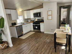 Kitchen featuring white cabinets, appliances with stainless steel finishes, dark wood finished floors, and wooden counters
